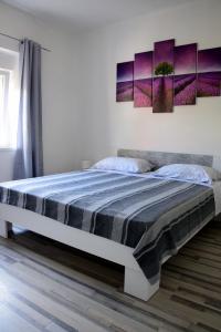 a bedroom with a large bed with purple paintings on the wall at Apartman Ana in Sali