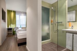 a bathroom with a shower and a bed and a sink at Super 8 by Wyndham Oberhausen am Centro in Oberhausen