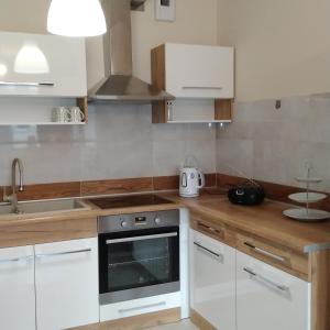 a kitchen with white cabinets and a stove top oven at Słoneczny - Mala Apartamenty in Wejherowo