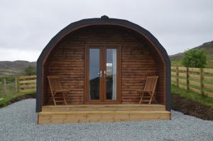 a wooden cabin with two chairs in the front at Glenview Lodge in Portree