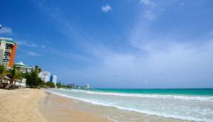 a sandy beach with buildings and the ocean at MAR DEL NORTE in San Juan