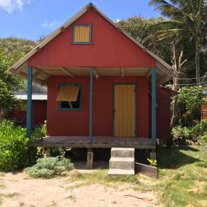 ein rotes Haus mit gelber Tür und Veranda in der Unterkunft Sunrise Paradise/Carlito´s Place in Corn Island