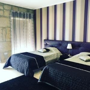 twee bedden in een slaapkamer met gestreepte muren bij Alojamento Galerias Nascentes in Alijó