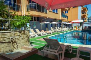 a swimming pool with a chair and a table and a building at Dara Hotel in Primorsko