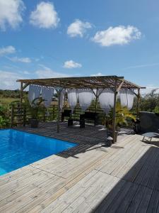 eine Holzterrasse mit Pergola und Swimmingpool in der Unterkunft La Villa Soleil :) in Sainte-Anne