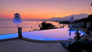 - une piscine avec vue sur l'océan au coucher du soleil dans l'établissement Princess of Mentigi Bay, à Teluknarat