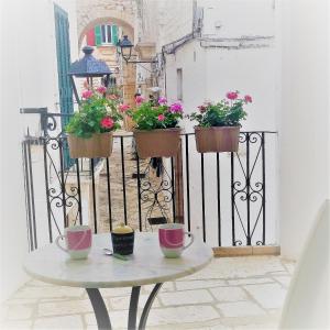 a table with three pots of flowers on a fence at Il Balcone di Giulietta in Locorotondo