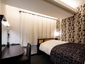 a hotel room with a bed and a desk and curtains at APA Hotel Komagome Ekimae in Tokyo
