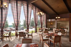 a restaurant with tables and chairs and large windows at Ramada by Wyndham Spokane Airport in Spokane