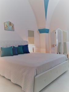 a white bedroom with a white bed with blue pillows at Il Balcone di Giulietta in Locorotondo