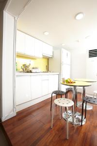 ソウルにある24 ゲストハウス ソウル ステーションの白いキャビネットとテーブルと椅子のあるキッチン