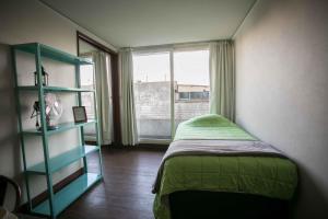 Un dormitorio con una cama verde y una ventana. en Apartments Zenteno, en Santiago
