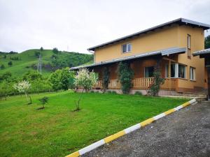 a house with a grassy yard and a yellow at Villa Meli in Visoko