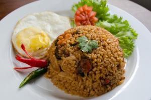 a white plate of food with rice and vegetables at The Rani Garden Bed & Breakfast in Denpasar +14 photos