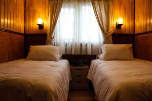 a bedroom with two beds and a window with curtains at Hotel Aliwen in Dalcahue
