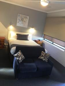 Habitación de hotel con cama y sofá en Nicholas Royal Motel - No Pets Allowed, en Hay