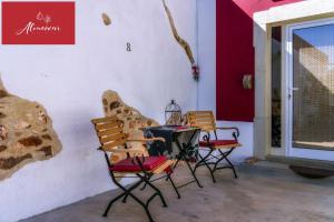 een tafel en stoelen in een kamer met een muur bij Guest House Almeixar in Almancil