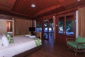 a bedroom with a bed and a chair in a room at Sylvia Beach Villa in Labuan Bajo