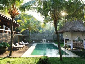 a swimming pool with palm trees and a house at Kalapa Boutique Resort & Yoga in Canggu