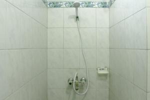 日惹RedDoorz Plus near Taman Sari 2的白色瓷砖浴室中带软管的淋浴