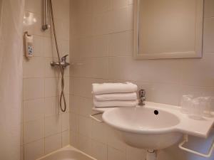La salle de bains est pourvue d'un lavabo, d'une douche et de serviettes. dans l'établissement ibis budget Redon, à Redon