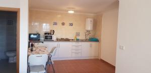 a kitchen with white cabinets and a table with a microwave at Casa Dom Yahya in Belmonte