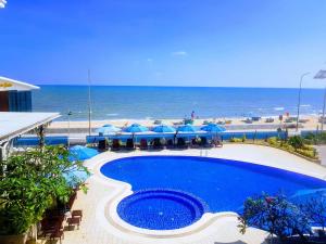 una piscina con sombrillas azules y la playa en Bella Vita Hotel, en Long Hai