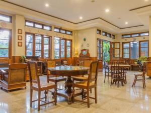 - une salle à manger avec des tables, des chaises et des fenêtres dans l'établissement RedDoorz near Simpang Dago 2, à Bandung