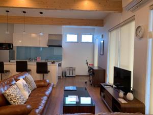 a living room with a couch and a table and a kitchen at Diamond Dust Furano in Furano