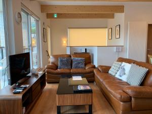 a living room with brown leather couches and a table at Diamond Dust Furano in Furano