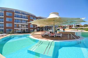 una piscina con sombrilla y sillas y un edificio en Apartment Gendar Delux, Sunny Island, Chernomorets en Chernomorets