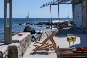 a table with a glass of wine next to the ocean at Sublime Villa & Caves in Akrotiri +116 photos