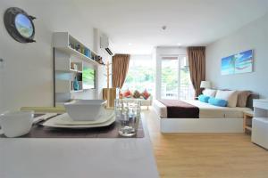 a white living room with a bed and a table at Ozone Condotel Kata Beach by PHR in Kata Beach