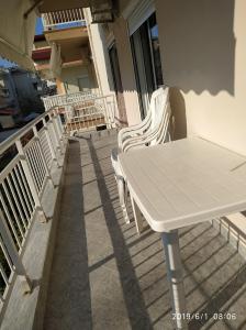 d'une table et de chaises blanches sur un balcon. dans l'établissement LAZAROS APARTMENTS, à Olympiakí Aktí