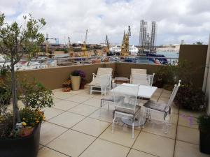 eine Terrasse mit einem Tisch und Stühlen sowie einem Hafen in der Unterkunft Three Cities Apartments in Cospicua