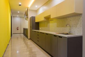 uma cozinha com um lavatório e uma parede amarela em RedDoorz Plus near Senayan City em Jakarta