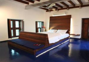 1 dormitorio con 1 cama grande y cabecero de madera en Tanjore Hi Hotel, en Thanjāvūr