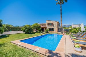 a swimming pool in front of a house with a palm tree at Caseta Lloseta in Lloseta