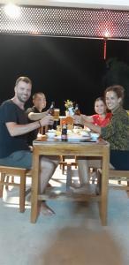 um grupo de pessoas sentadas em torno de uma mesa de madeira em Fami Homestay em Phong Nha