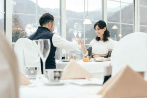 un homme servant une femme à une table dans un restaurant dans l'établissement Engel Gourmet&Spa, à Nova Levante