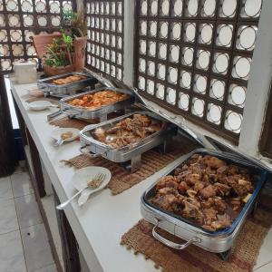 ein Buffet mit mehreren Tabletts Essen auf der Theke in der Unterkunft Raya Del Sol Dive Resort in Mabini