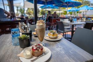 een houten tafel met twee borden eten en een shake bij Karrinyup Waters Resort in Perth