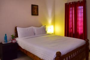 Schlafzimmer mit einem großen Bett und roten Vorhängen in der Unterkunft Villa Gomez in Puducherry