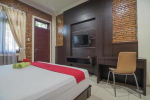 a bedroom with a bed and a tv and a chair at RedDoorz Plus near Cambridge City Square 2 Medan in Medan