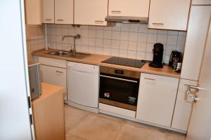 une petite cuisine avec des armoires blanches et un évier dans l'établissement Vicky´s Ferienwohnung, à Flensbourg