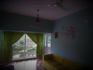 a living room with a couch and a large window at Honeybee residency Vagamon in Vagamon