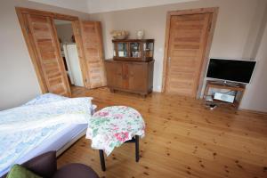 a bedroom with two beds and a tv and wooden floors at Ferienwohnung Fläming in Bad Belzig