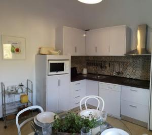 a kitchen with white cabinets and a table with chairs at Casa con Cuevita in Teror