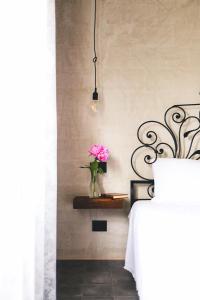 a vase of pink flowers sitting on a shelf next to a bed at Fuoricittà in Povegliano Veronese