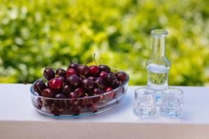 a bowl of cherries and a bottle of water and glasses at Dionyssos Rooms Preveli Crete in Preveli